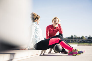 Junge Frauen, die am Flussufer sitzen und nach dem Training eine Pause einlegen - MOEF01676