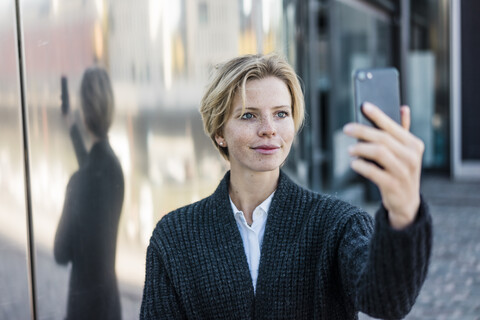 Junge Geschäftsfrau macht Selfie mit ihrem Smartphone, lizenzfreies Stockfoto