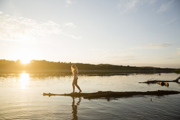 Seitenansicht einer jungen Frau im Bikini, die am Flussufer steht, gegen den Himmel bei Sonnenuntergang - CAVF56481