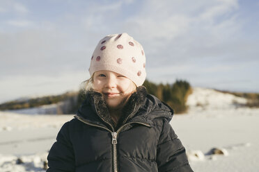 Porträt eines niedlichen Mädchens, das warme Kleidung trägt und im Winter blinzelt - CAVF56539