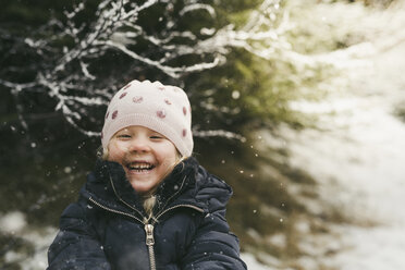Cheerful girl playing outdoors during winter - CAVF56544