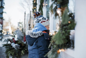 Seitenansicht eines Jungen in warmer Kleidung vor einem Haus - CAVF56552