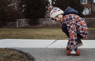 Porträt eines Jungen, der auf dem Fußweg im Park Skateboard fährt - CAVF56553