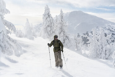 Mann mit Skiausrüstung in voller Länge auf einem schneebedeckten Berg bei nebligem Wetter - CAVF56564