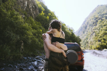 Paar umarmt beim Küssen gegen Berge - CAVF56593