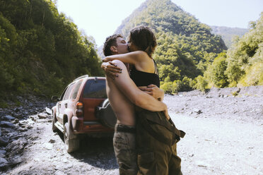 Seitenansicht eines Paares, das sich küssend vor Bergen umarmt - CAVF56594