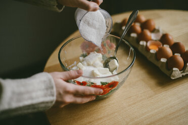 Cropped hands of woman making batter in bowl on wooden table at home - CAVF56597