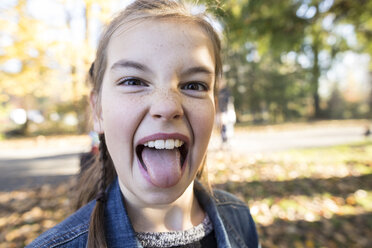 Close-up portrait of girl sticking out tongue while standing at park - CAVF56605