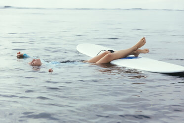 Woman with eyes closed floating while surfing on sea - CAVF56620