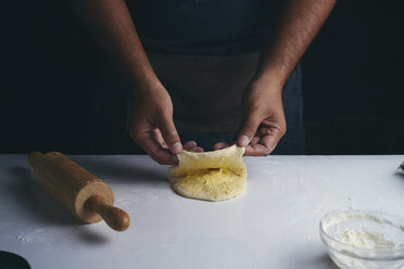 Mittelteil eines Mannes, der in einer Bäckerei stehend Essen am Tisch zubereitet - CAVF56626
