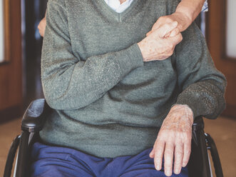 Midsection of senior man holding woman hand while sitting on wheelchair - CAVF56633