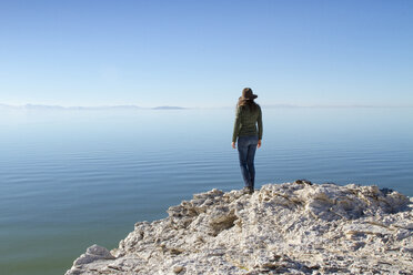 Rear view of woman standing on rock at Antelope Island against clear blue sky - CAVF56640