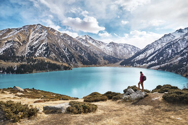 In voller Länge von Backpacker Blick auf die Aussicht, während stehend am See gegen Berge und bewölkten Himmel im Winter - CAVF56664