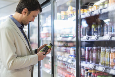 Älterer Mann im Supermarkt wählt Smoothie aus dem Kühlregal - DIGF05489