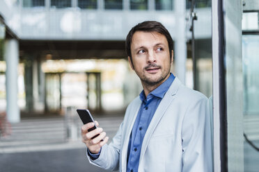 Portrait of a businessman using smartphone in the city - DIGF05495