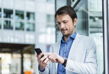 Portrait of a businessman using smartphone in the city - DIGF05496