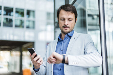 Portrait of a businessman checkin time, using smartphone - DIGF05497