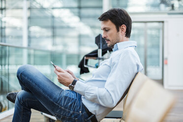 Businessman waiting in airport departure area, using digital tablet - DIGF05525