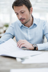 Businessman working in office, reading documents - DIGF05537