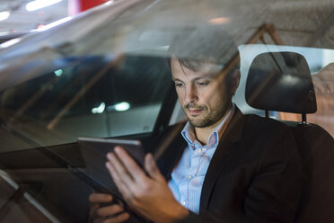 Geschäftsmann sitzt nachts im Auto und benutzt ein digitales Tablet - DIGF05554