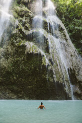 Rückansicht eines im Fluss schwimmenden Mannes ohne Hemd am Wasserfall - CAVF56688