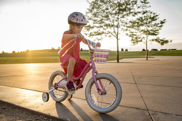 Selbstbewusstes Mädchen, das im Park bei klarem Himmel Fahrradfahren lernt - CAVF56707