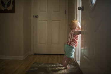 Side view of baby boy looking though door - CAVF56721