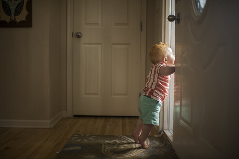 Seitenansicht eines kleinen Jungen, der durch die Tür schaut - CAVF56721