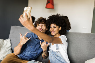 Glückliches Paar sitzt auf der Couch und macht ein Selfie - VABF01862