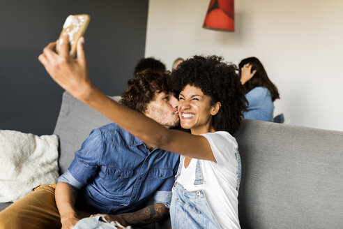 Glückliches Paar sitzt auf der Couch und macht ein Selfie - VABF01863