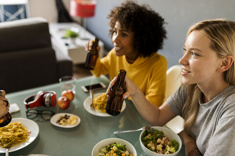 Freundinnen sitzen am Tisch, essen und trinken Bier, lizenzfreies Stockfoto