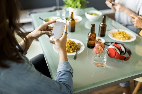 Nahaufnahme von Freunden, die am Tisch sitzen und Handys benutzen, lizenzfreies Stockfoto