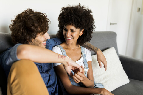 Glückliches Paar sitzt auf der Couch und spricht, lizenzfreies Stockfoto