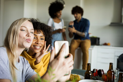 Happy girlfriends sitting at dining table taking a selfie stock photo