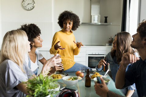 Friends sitting at table talking, eating and drinking beer stock photo