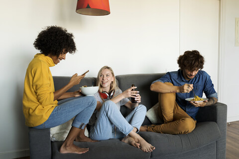 Friends sitting on couch eating and drinking stock photo