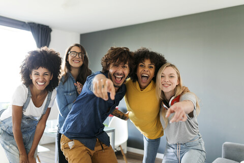 Porträt von fröhlichen Freunden zu Hause mit Mann und Frau, die mit dem Finger zeigen, lizenzfreies Stockfoto