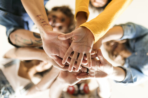 Group of happy friends huddling and stacking hands stock photo