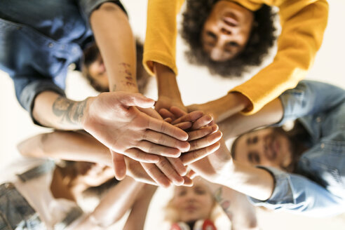 Group of happy friends huddling and stacking hands - VABF01913