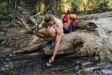 Junger Wanderer schöpft frisches Wasser in einem Wald - VPIF01170