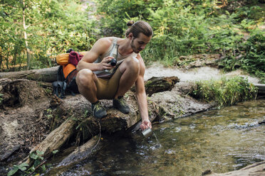 Junger Wanderer schöpft frisches Wasser in einem Wald - VPIF01171