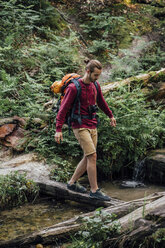 Young hiker with backpack crossing water in the forest - VPIF01176