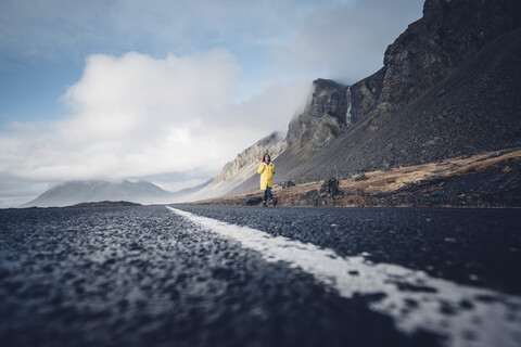 Island, Frau geht auf der Fahrbahn einer Landstraße, lizenzfreies Stockfoto