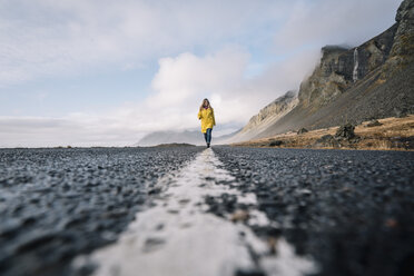 Island, Frau geht auf dem Mittelstreifen einer Landstraße - OCMF00122