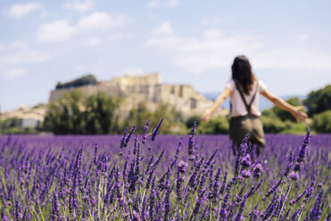 France, Grignan, back view of woman standing in lavender field - GEMF02595