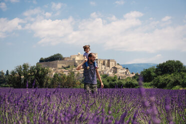 France, Grignan, father carrying little daughter on his shoulders through lavender field - GEMF02602