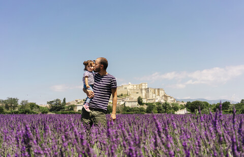 Frankreich, Grignan, Vater küsst seine kleine Tochter im Lavendelfeld, lizenzfreies Stockfoto