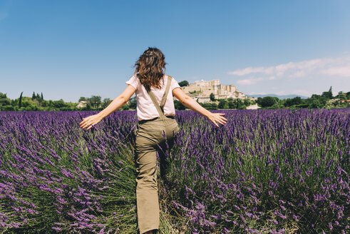 Frankreich, Grignan, Rückenansicht einer Frau beim Überqueren eines Lavendelfeldes - GEMF02615