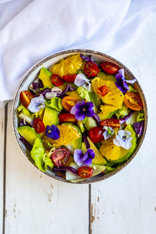 Schüssel mit gemischtem Salat mit Avocado, Tomaten und essbaren Blüten, lizenzfreies Stockfoto