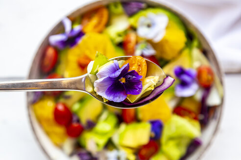 Spoon of mixed salad with avocado, tomatoes and edible flower, close-up - SARF03984
